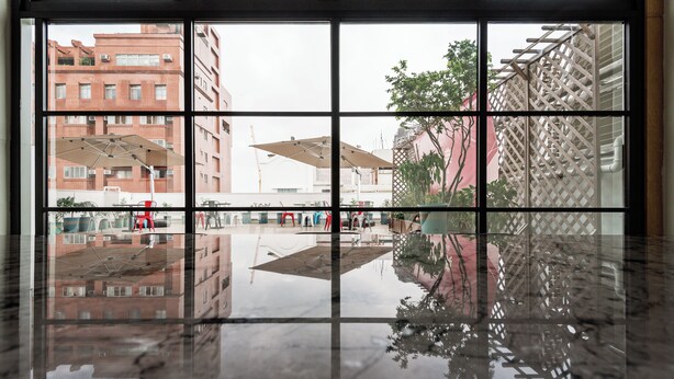 A view through a window with a clear reflection of buildings and a tree, indicating a view of the cityscape. - SATURN HOTEL (Taichung)