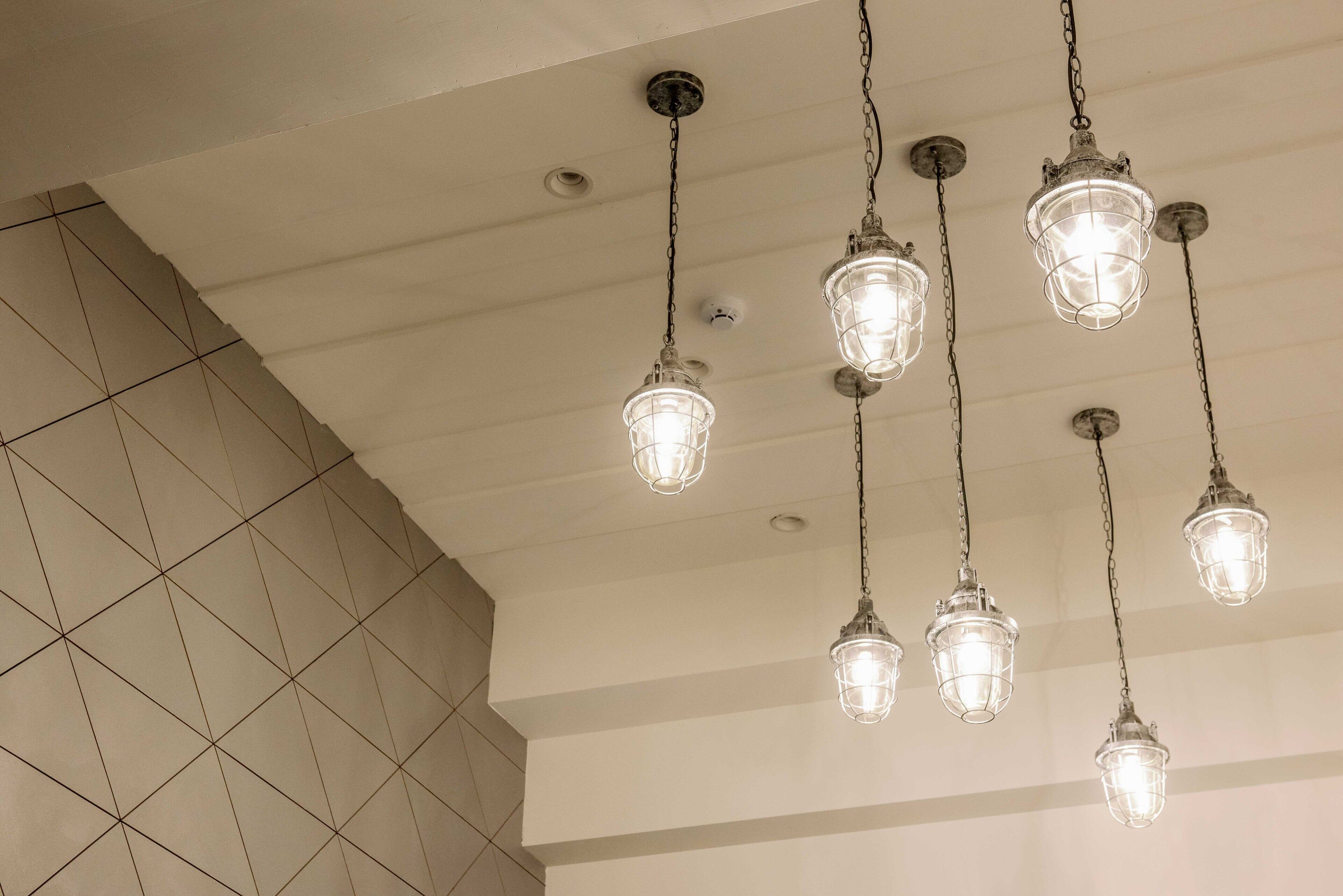 A ceiling with multiple hanging light fixtures and a tiled wall.