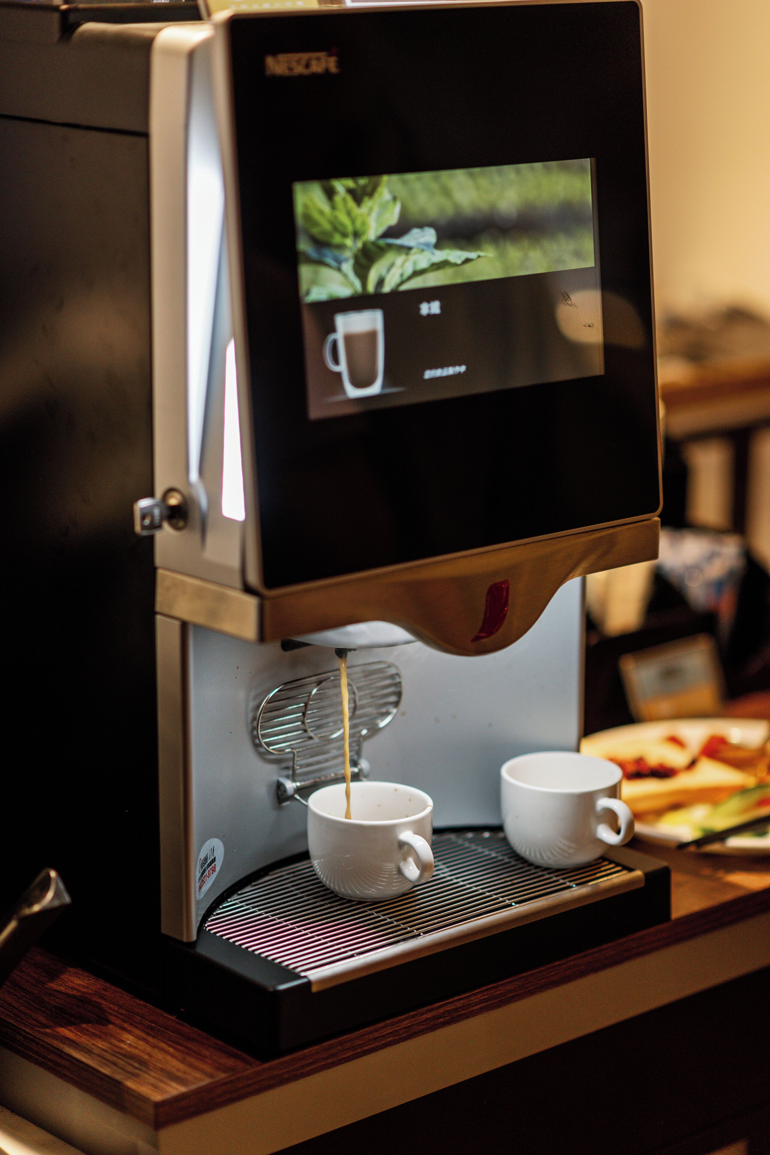 A coffee machine with two white cups placed below it.