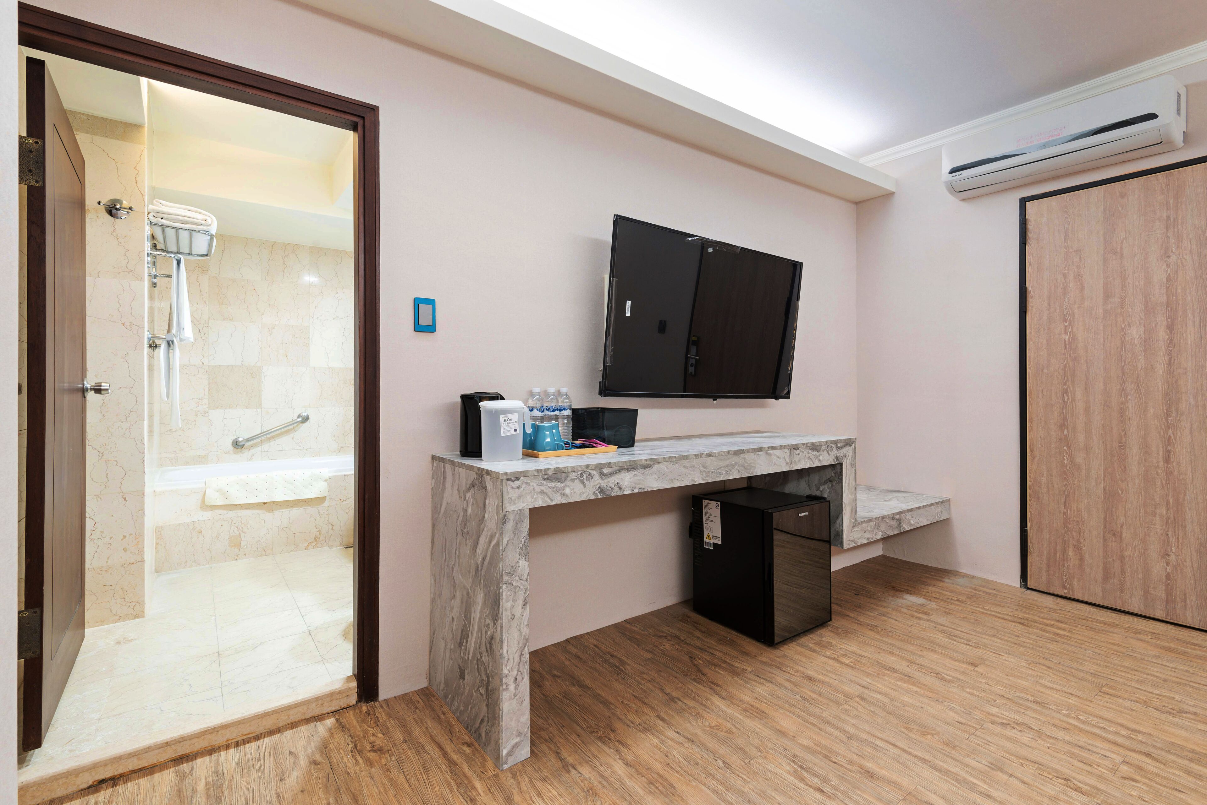 A bathroom with a shower, a vanity with a mirror, and a small refrigerator.
