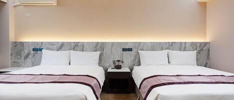 Ein Hotelzimmer mit zwei Betten, einem Marmorkopfstück, Nachttischen und einer Klimaanlage.