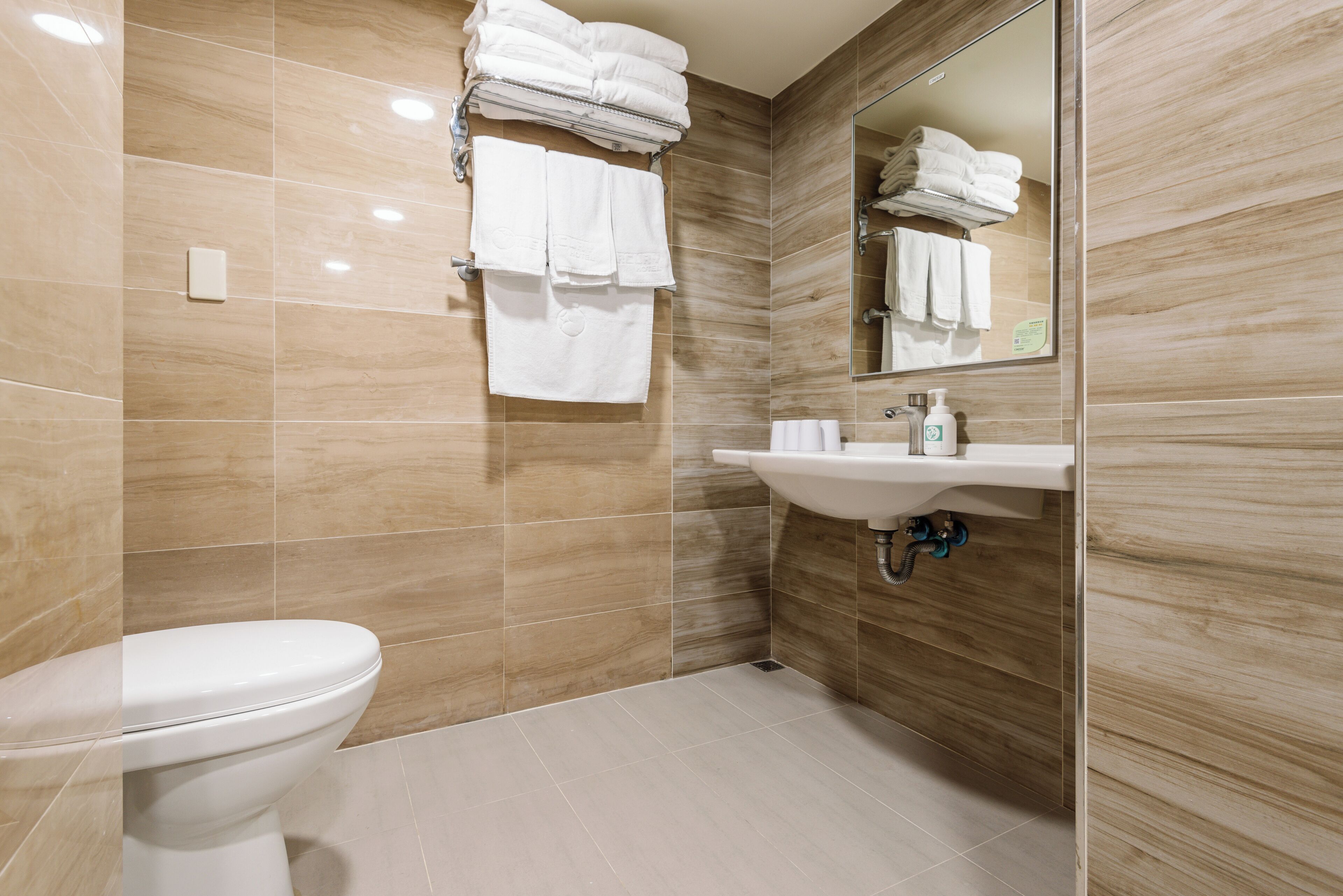 A modern bathroom with a toilet, sink, and stacked towels.