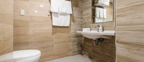 A modern bathroom with a toilet, sink, and stacked towels.