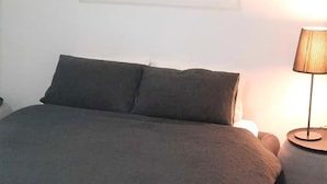 Ett sovrum med en stor säng, ett nattduksbord och en lampa.