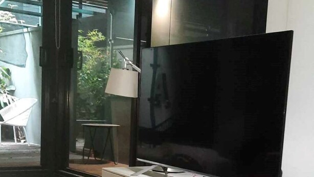 Ett modernt vardagsrum med en stor platt-TV som är monterad på ett vitt skåp.