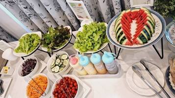 A buffet table with various food items including salads, fruits, and beverages.