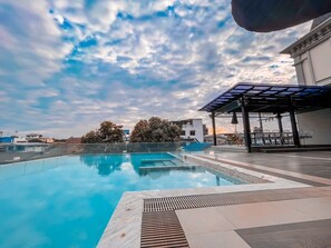 A rooftop infinity pool with a clear view of the sky and surrounding buildings.