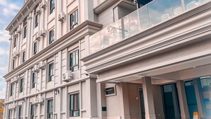 Un edificio de varios pisos con estilo arquitectónico clásico, que cuenta con un balcón con barandilla de vidrio y una moderna extensión de cristal.