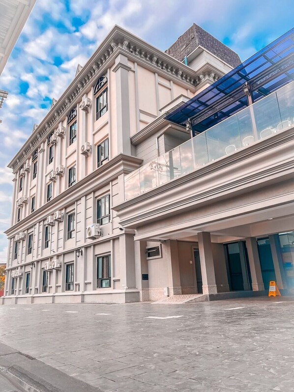 A multi-story building with a classical architectural style, featuring a balcony with glass railings and a modern glass extension. - Huern Kan Thong Hotel (Phrae)