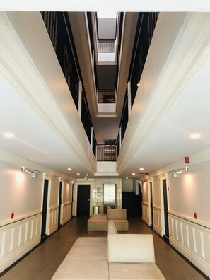 A spacious interior with a central seating area, a high ceiling, and a view to an upper floor. - Huern Kan Thong Hotel (Phrae)