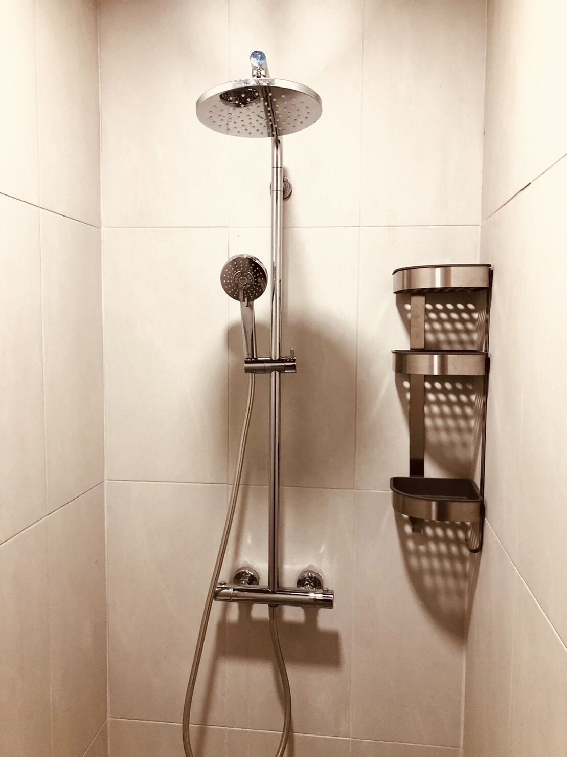 Een douche met een handdouche en een wandmengkraan.