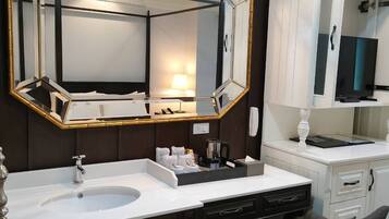 A modern bathroom with a large mirror, dark wood cabinets, a white vanity, and a black chair.