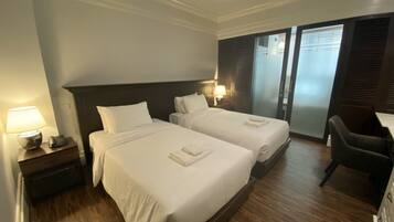 A hotel room with two beds, a desk, and a chair.