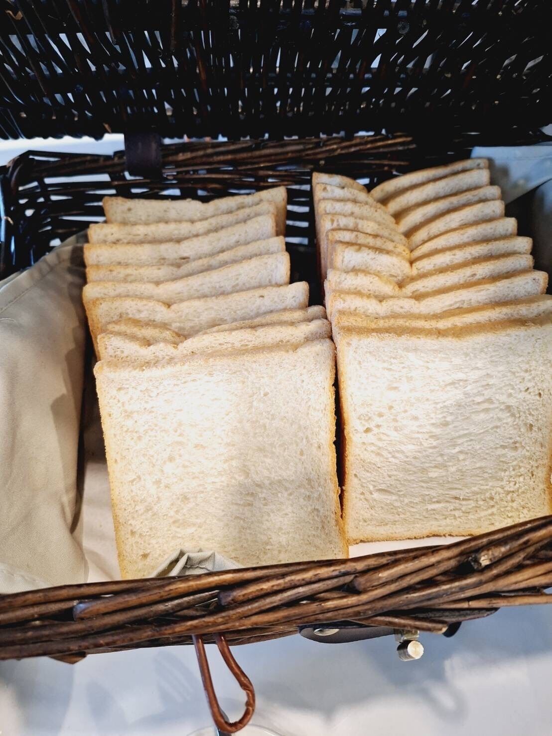 Una cesta de mimbre con varias hogazas de pan blanco.