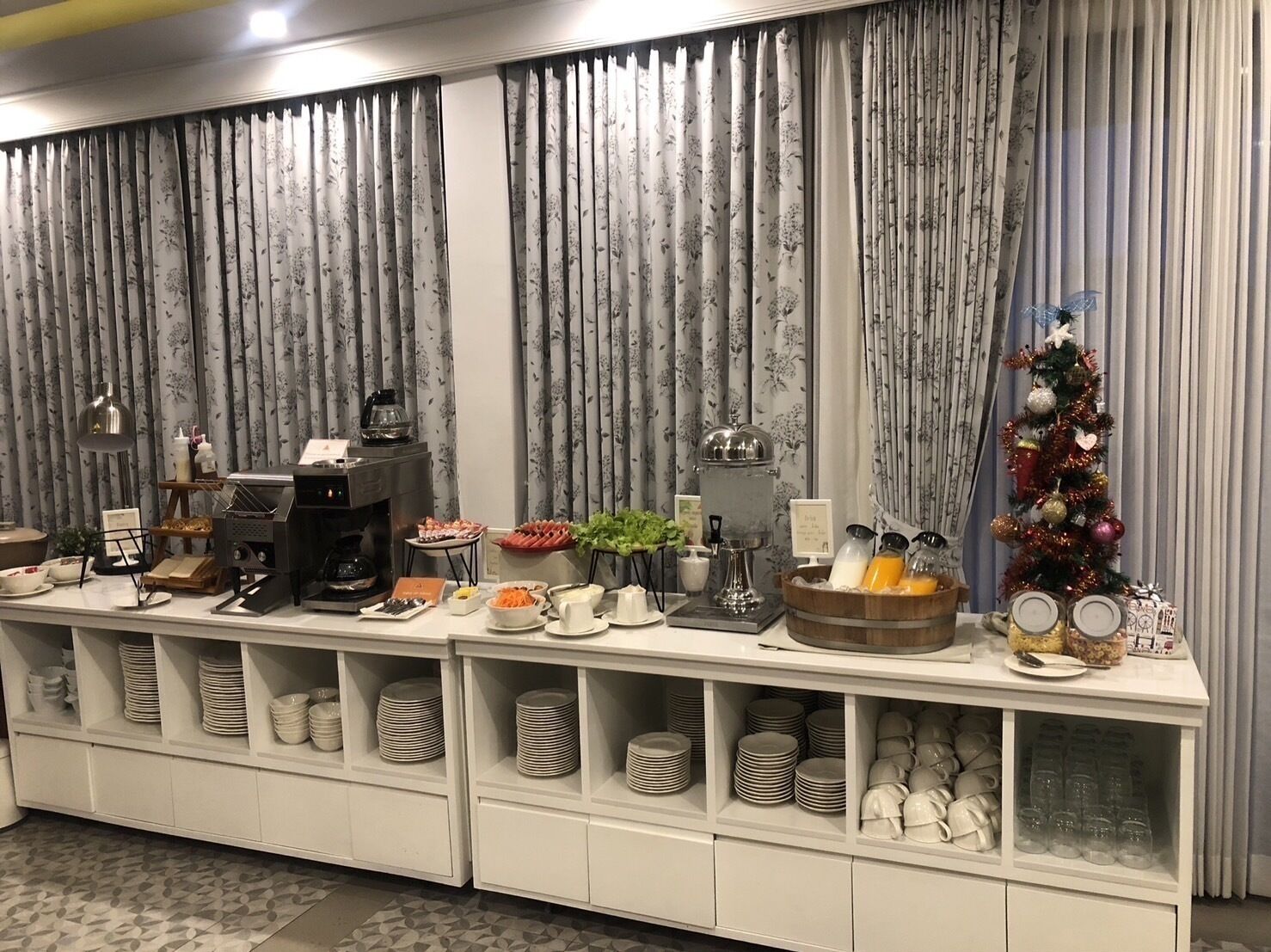 A buffet setup with various food items, a coffee station, and a Christmas tree.