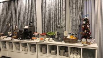 A buffet setup with various food items, a coffee station, and a Christmas tree.