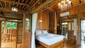 A wooden cabin with a large bed, wooden furniture, and a balcony.
