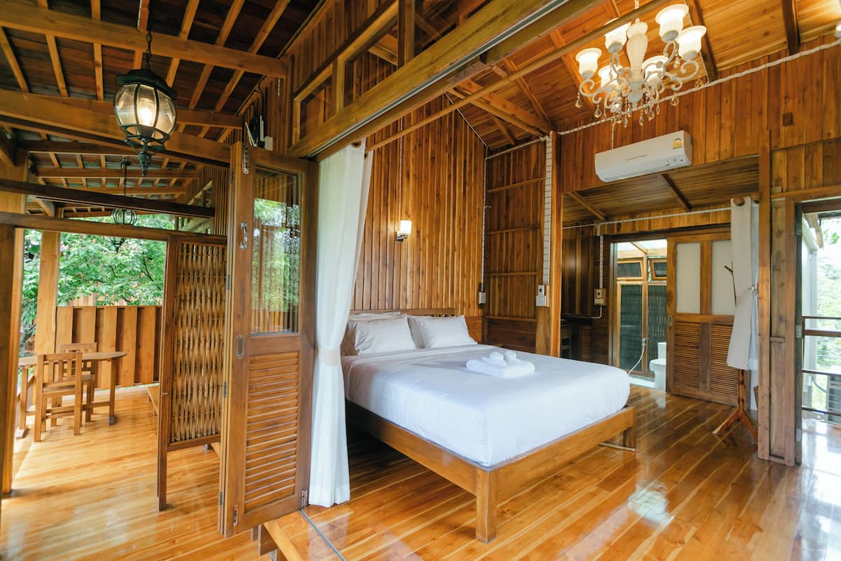 A wooden cabin with a large bed, wooden furniture, and a balcony.
