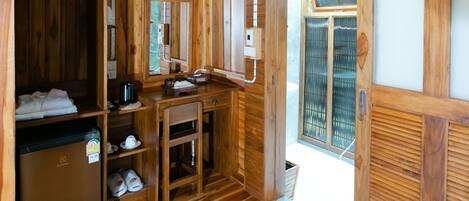 A wooden interior with a wooden floor, a sink, a mirror, and a door leading outside.