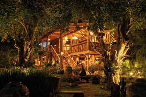 A large, rustic wooden building with multiple levels, surrounded by lush greenery and potted plants. - Saksila Resort (Pua)