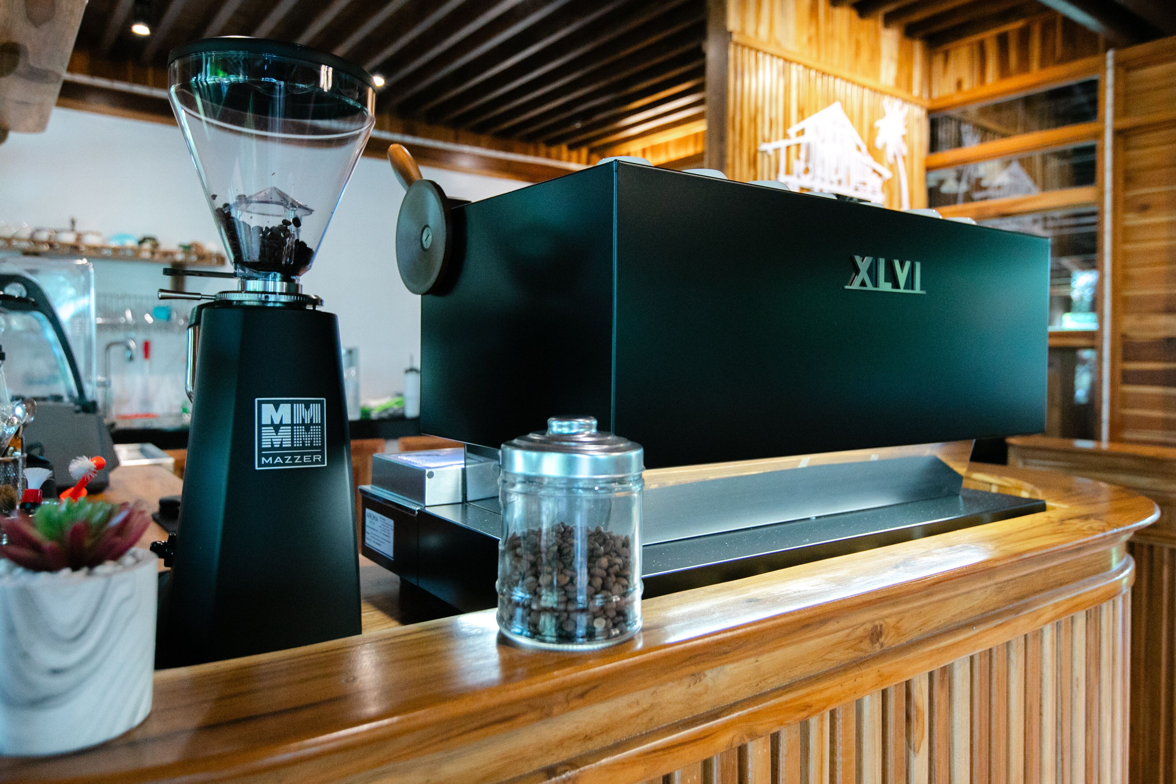 A coffee machine and a glass container of coffee beans on a wooden counter.