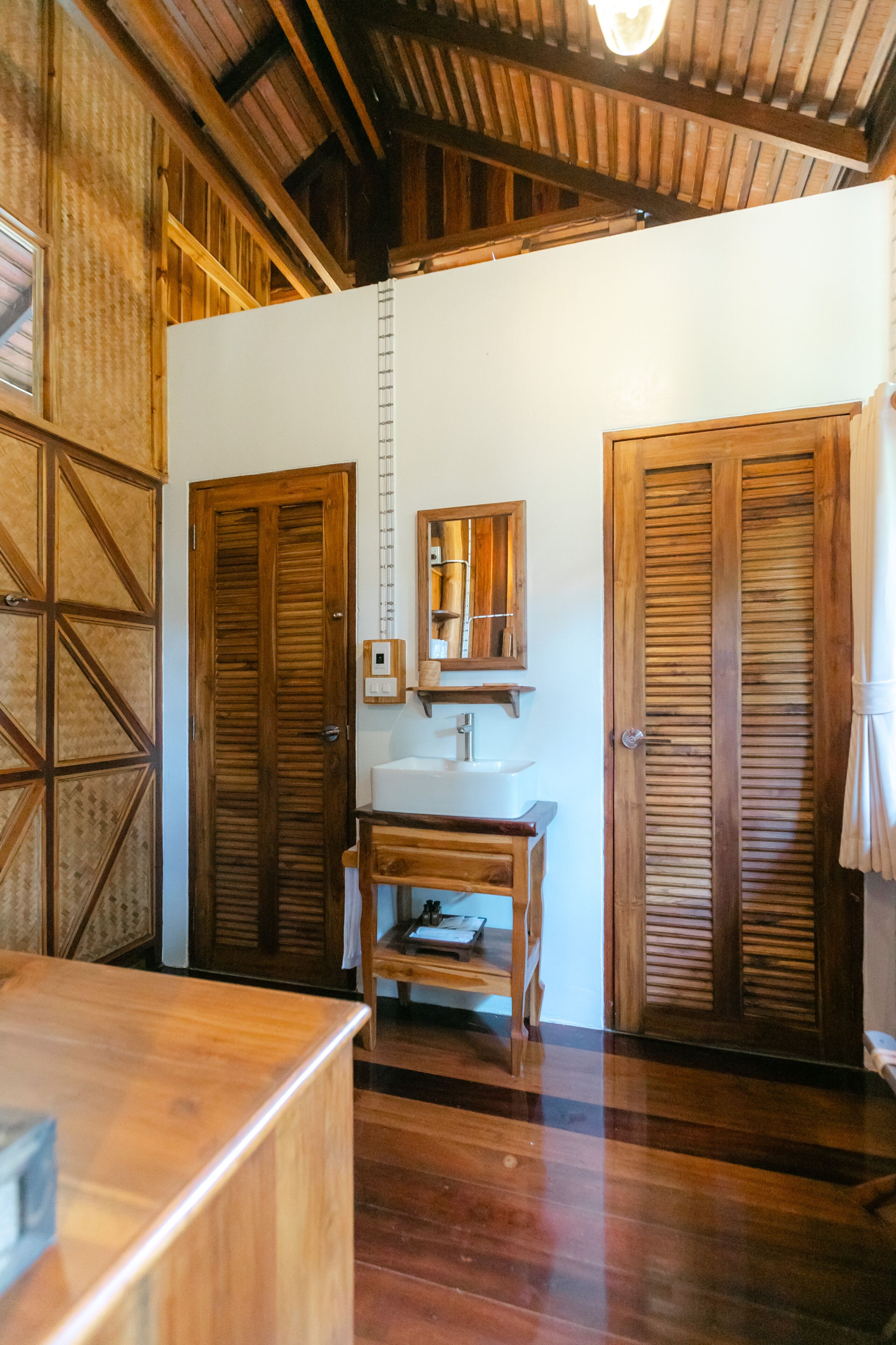 A wooden bathroom with a sink, mirror, and two doors.