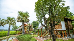 A resort with wooden structures, a water feature, and lush greenery.