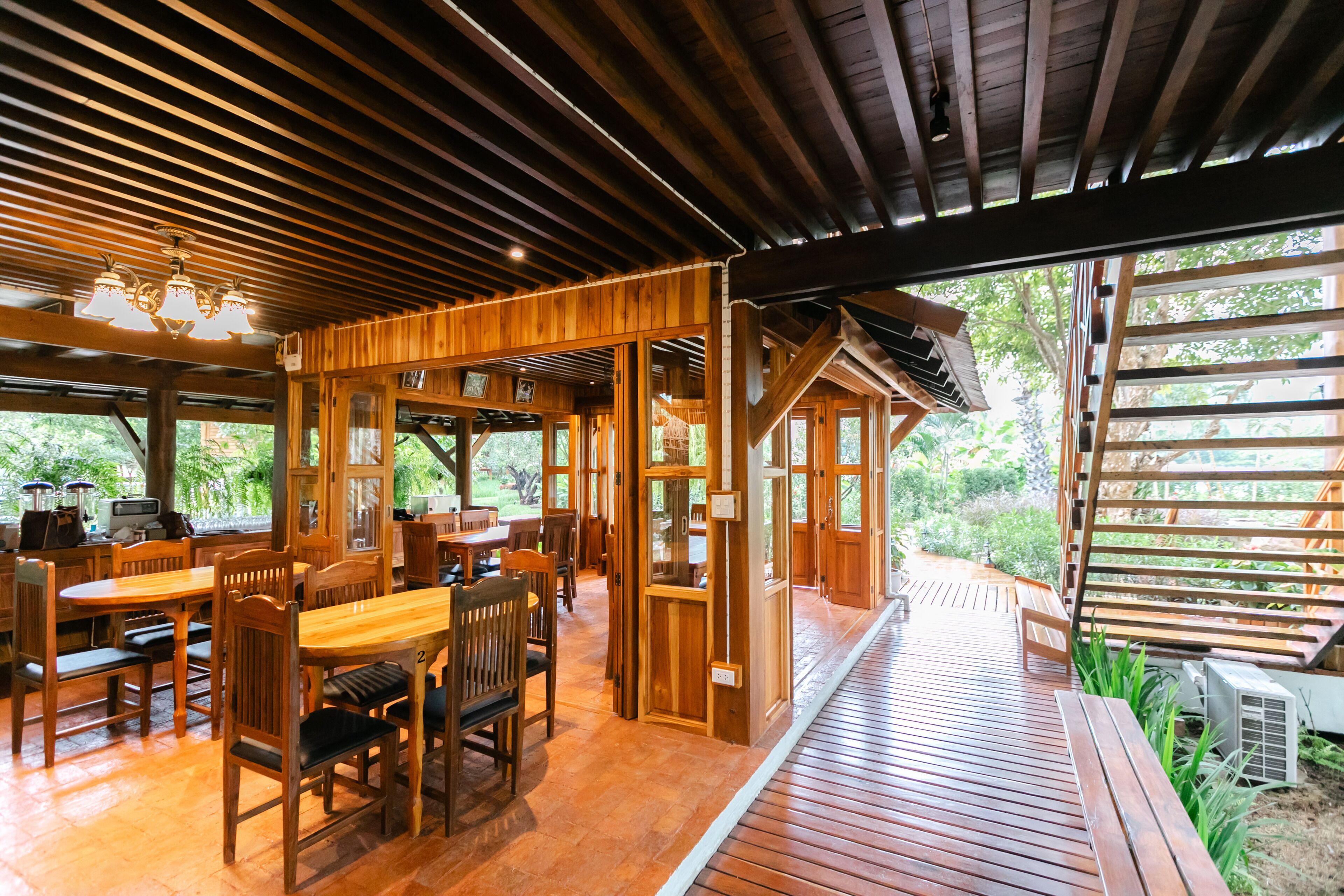 Un intérieur en bois comprenant un coin repas, une cuisine et une vue sur la verdure environnante.