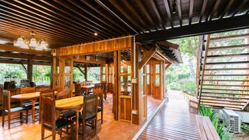 Un intérieur en bois comprenant un coin repas, une cuisine et une vue sur la verdure environnante.