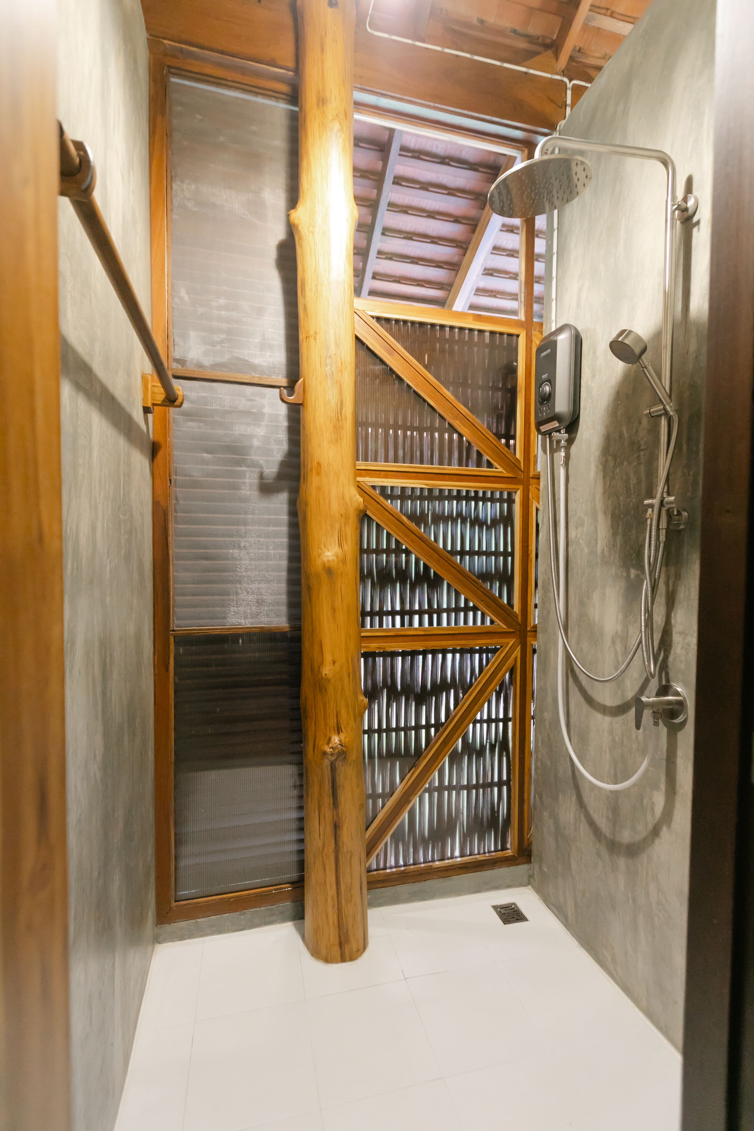 Zona de ducha con puerta de madera y paredes metálicas, que incluye un cabezal de ducha y un rociador de mano.