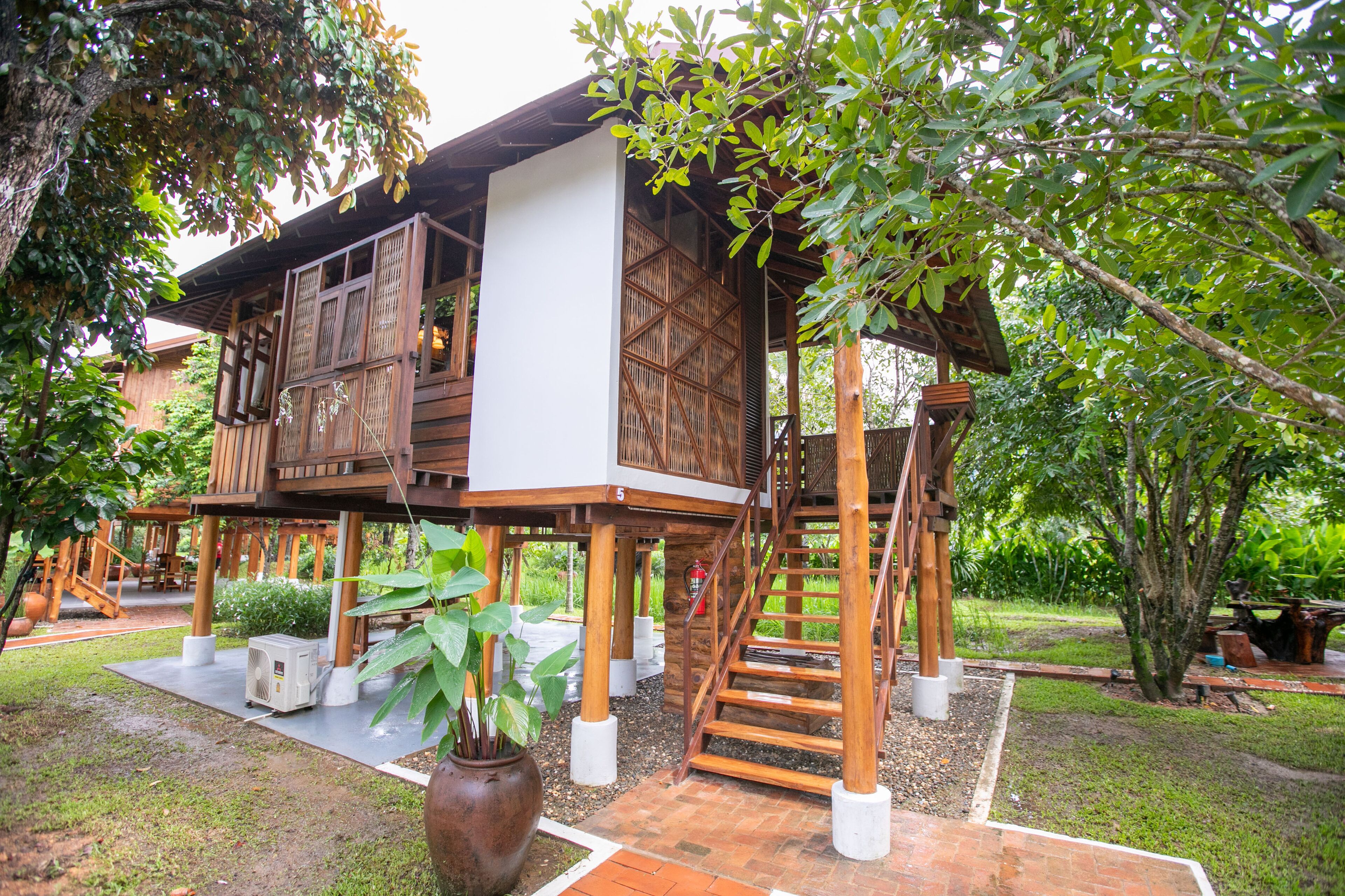 A wooden house with a balcony, a staircase, and a potted plant.