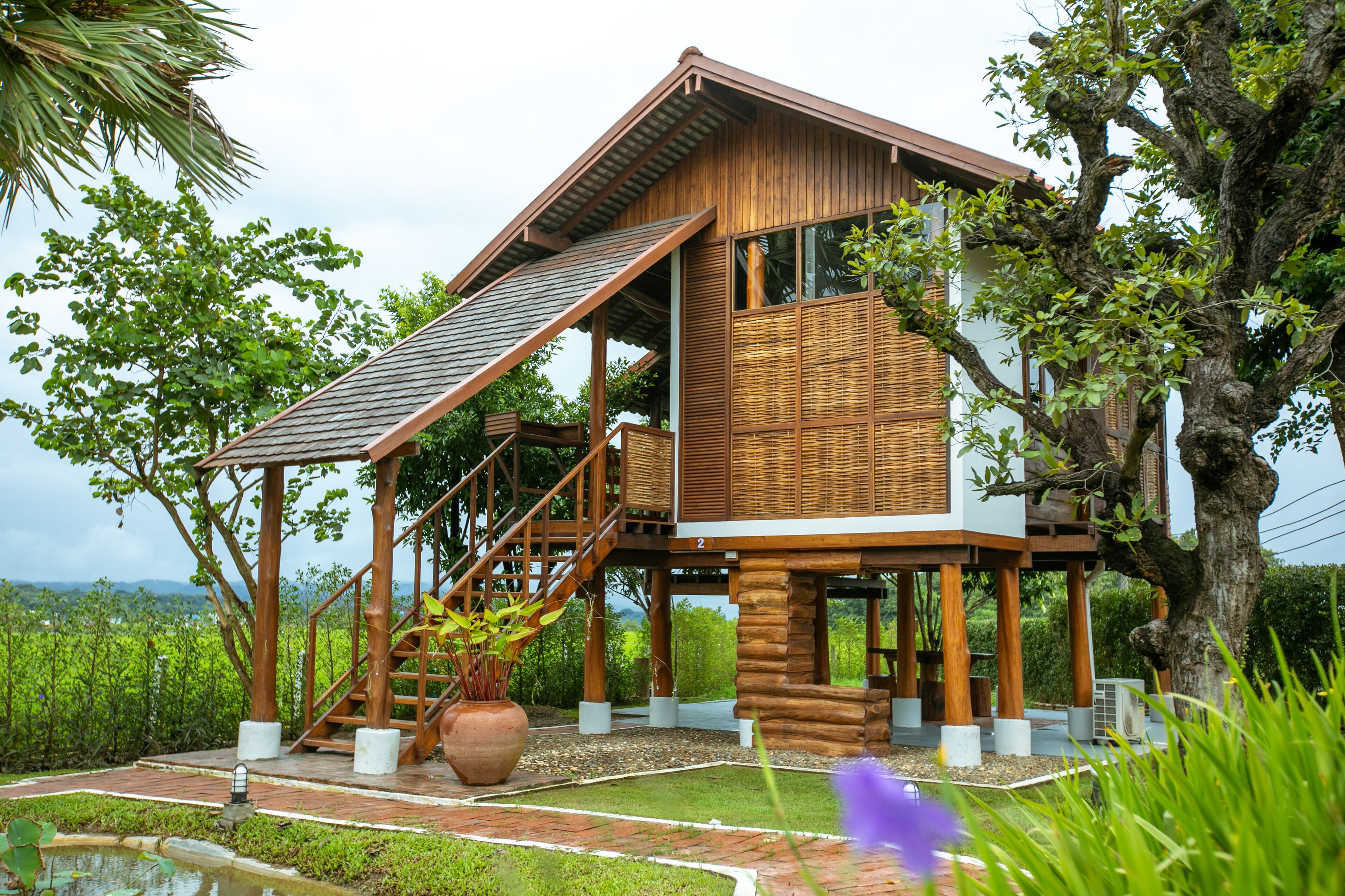 A two-story wooden house with a balcony, a staircase, and a large window.