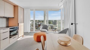 Una cocina moderna con comedor, ventanas amplias y vistas a un paisaje urbano.