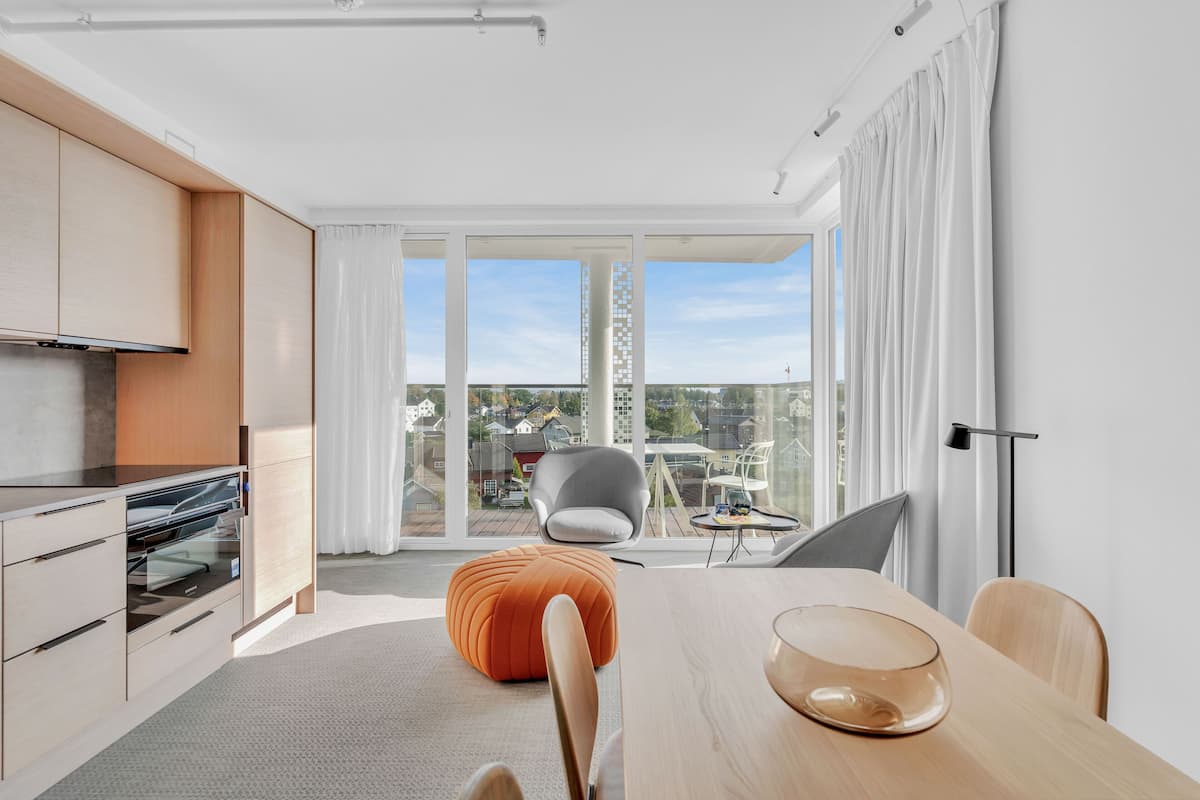 Una cocina moderna con comedor, ventanas amplias y vistas a un paisaje urbano.