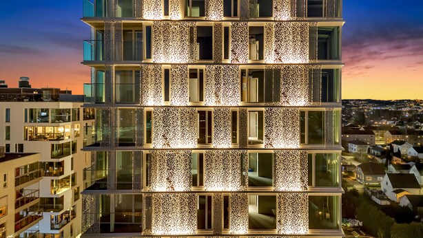 Un edificio de varios pisos con balcones de vidrio reflectante y fachada con diseño.