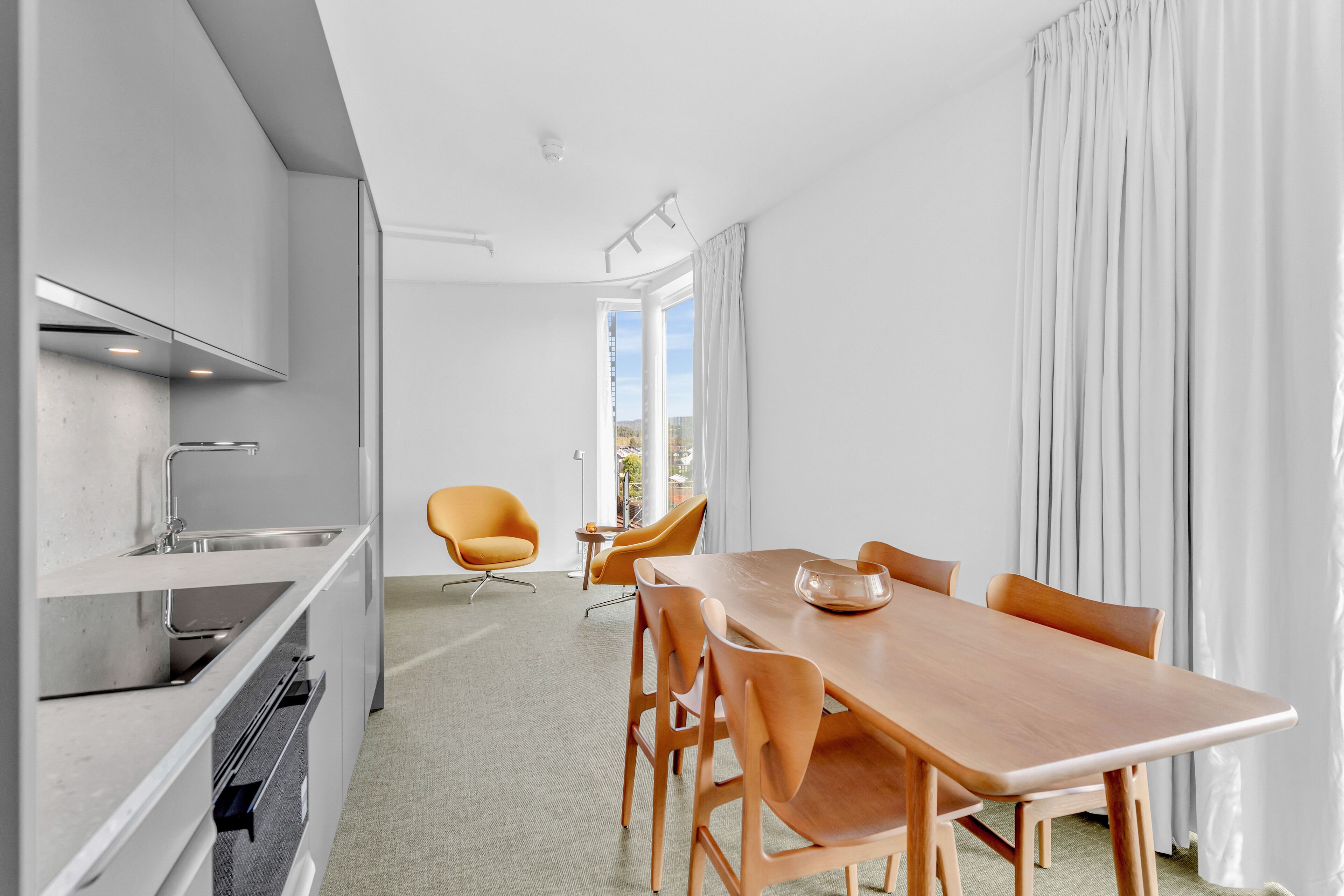 Una cocina moderna con comedor, que incluye una mesa grande y sillas, horno empotrado y vista al exterior.