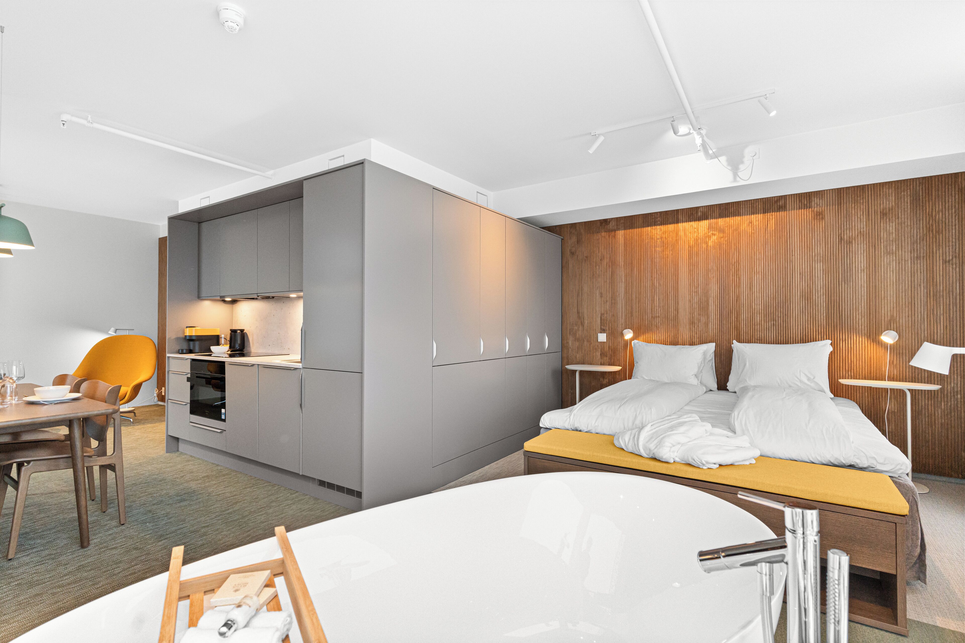 Una habitación de hotel moderna con cama, escritorio y kitchenette.