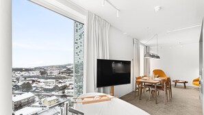 Una habitación de hotel moderna con un amplio ventanal, televisor de pantalla plana, zona de comedor y bañera.