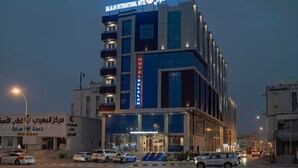 Un moderno edificio de hotel con varios pisos, un letrero destacado que dice "SALALAH INTERNATIONAL HOTEL" y una entrada visible con escalones que llevan a ella.