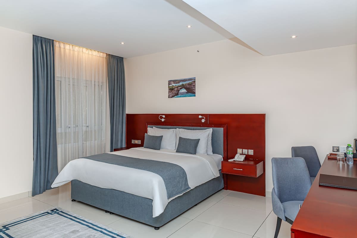 Una habitación de hotel con una cama grande, un escritorio, una silla y un cuadro en la pared.