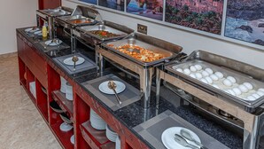 Montaje tipo bufé con diferentes estaciones de comida, que incluyen una barra de pastas, una barra de ensaladas y una exhibición de frutas.