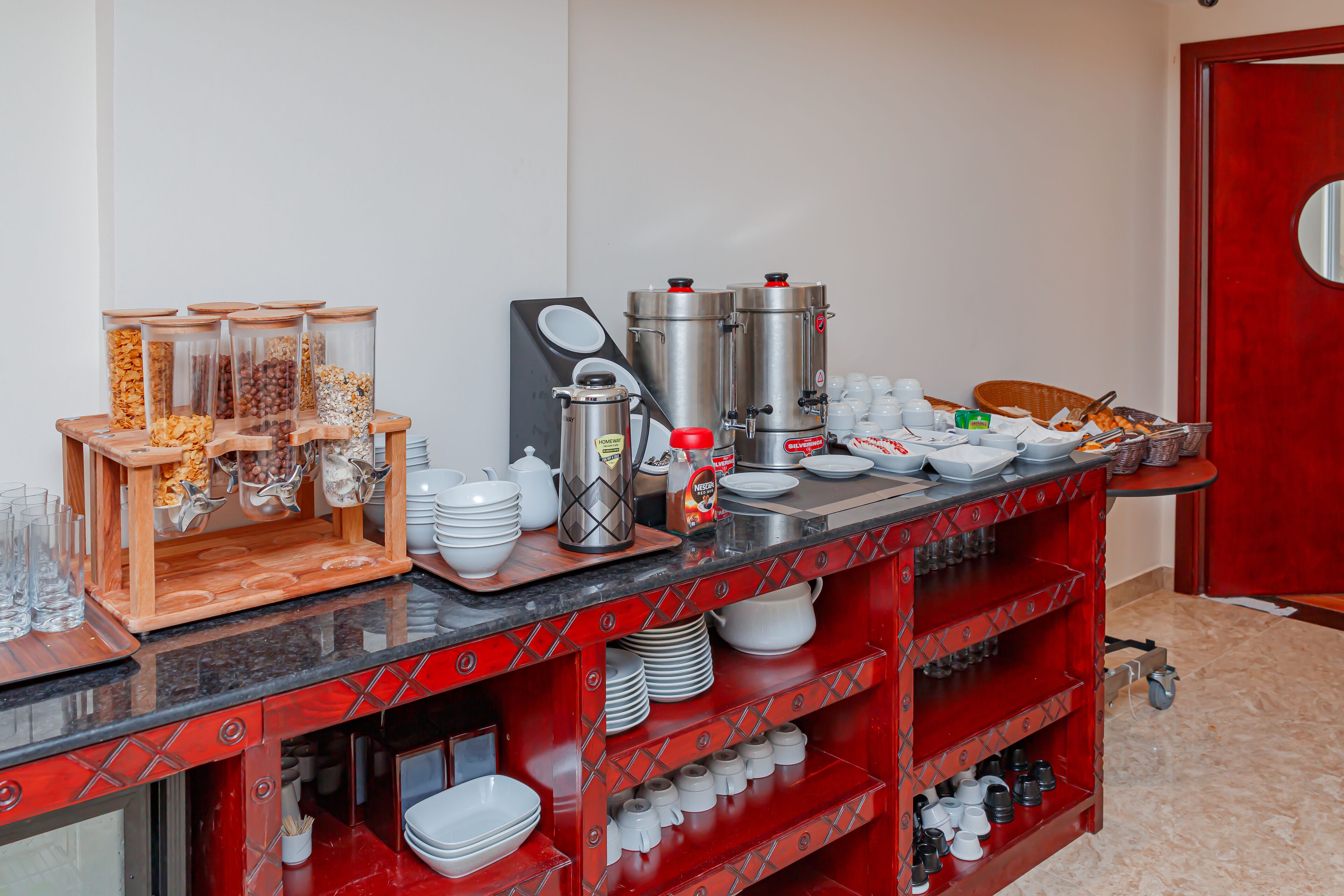 Zona de petit esmorzar amb diverses opcions de menjar, màquines de cafè i utensilis.