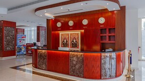 Una recepción con relojes que marcan la hora en Londres, Tokio y Macao, un panel que imita el mármol y un acabado de madera roja.