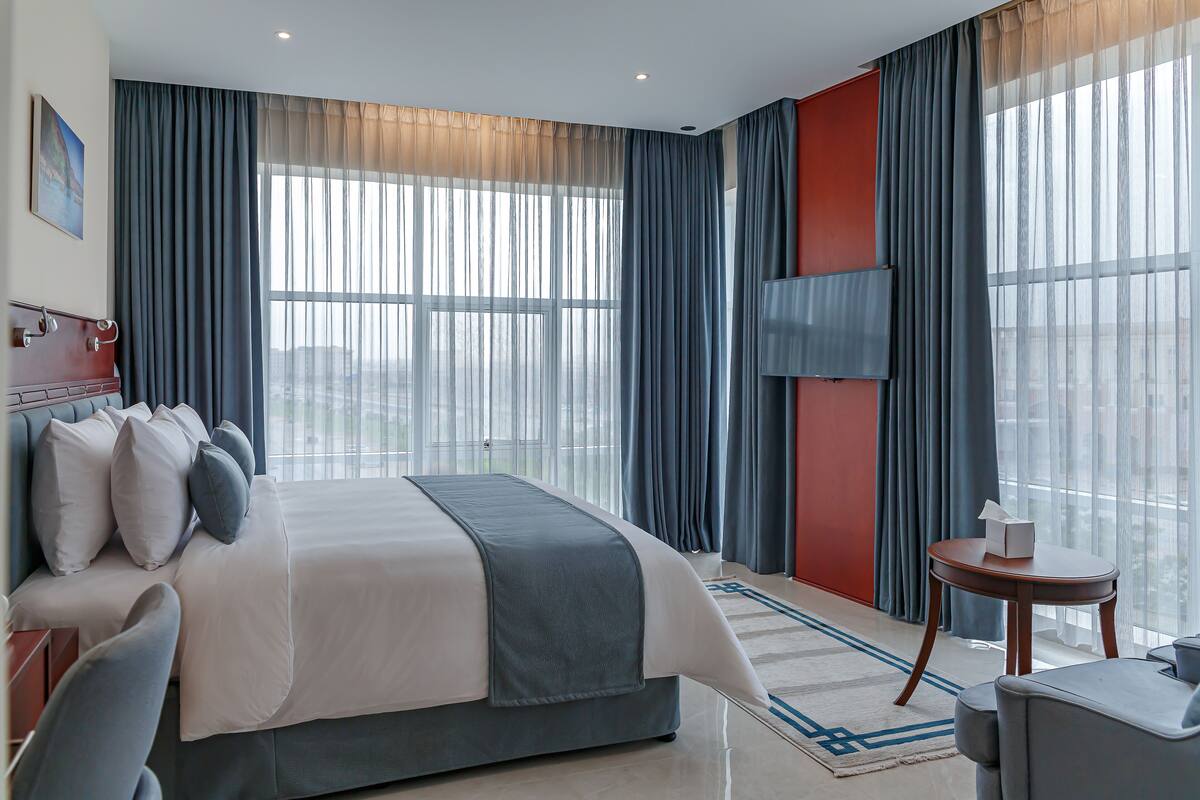 Una habitación de hotel moderna con una cama grande, un escritorio y vistas a la ciudad.