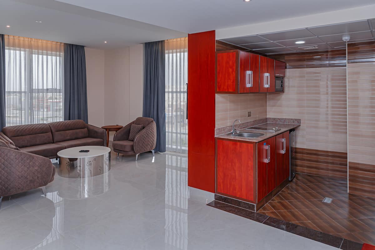 Una sala moderna con un sofá, una mesa de centro y una cocina con armarios rojos y un lavabo.