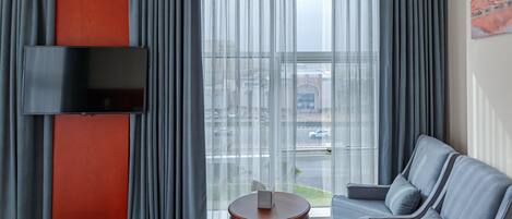 Un salon moderne avec un canapé, une petite table ronde et un téléviseur à écran plat fixé au mur.