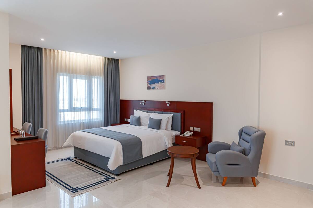 Una habitación de hotel moderna con una cama grande, un escritorio, una silla y una mesita.