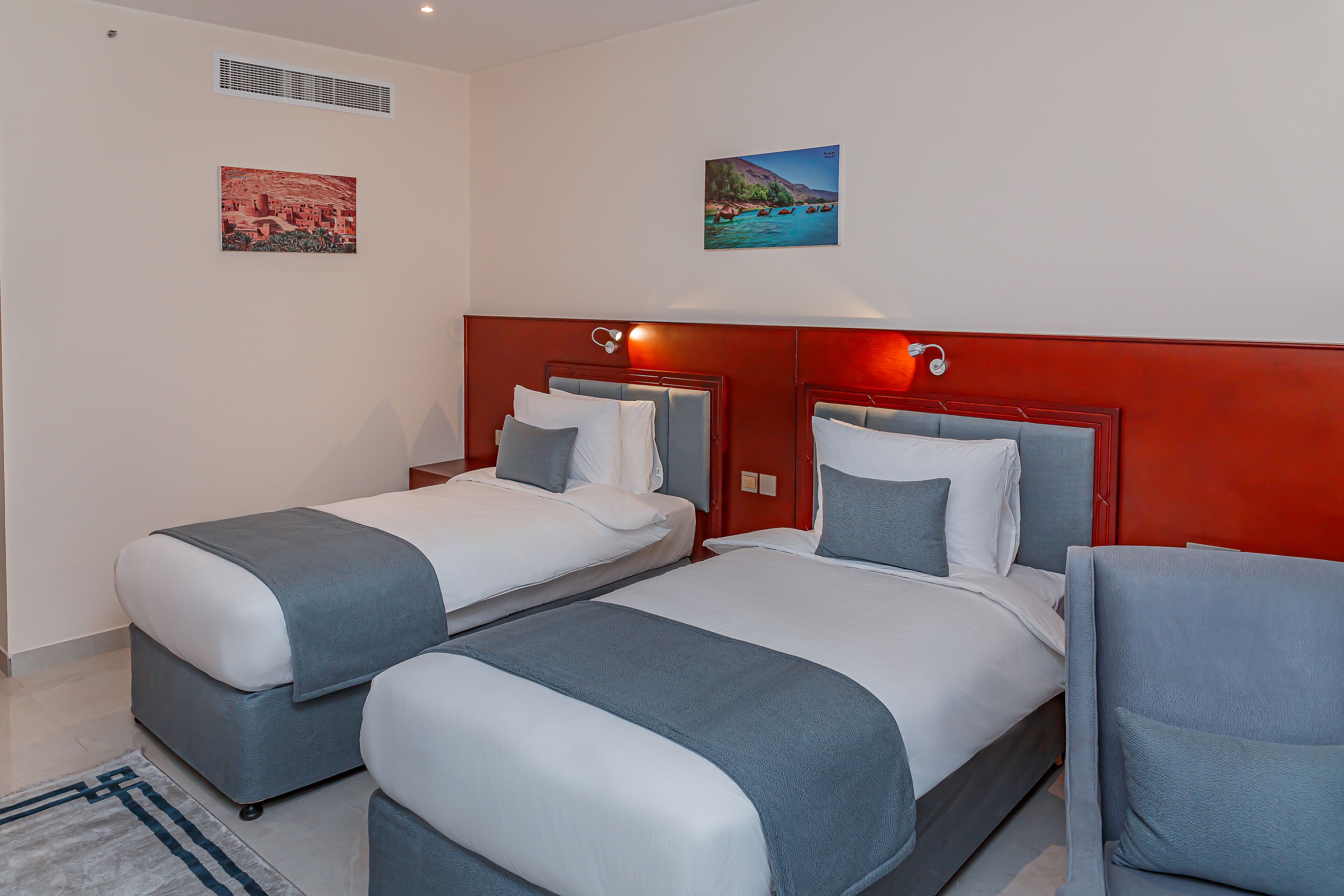 Een hotelkamer met twee bedden, een rode accentmuur en kunstwerken aan de wanden.