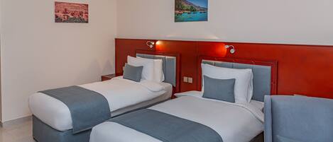 Een hotelkamer met twee bedden, een rode accentmuur en kunstwerken aan de wanden.