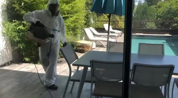 A person in protective gear near a pool area with outdoor seating and a table.